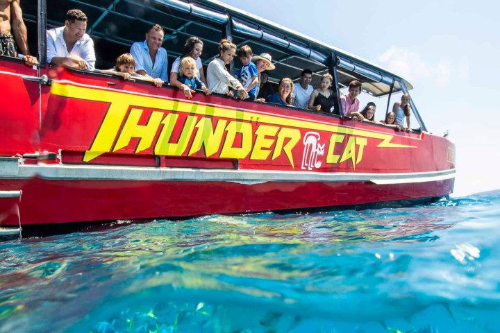 Guests on a red boat looking at fish in the water at Mantaray Bay