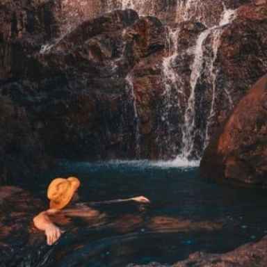a man sitting on a rock next to water