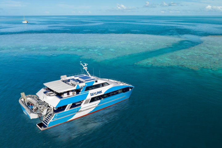 a blue and white boat sitting next to a body of water