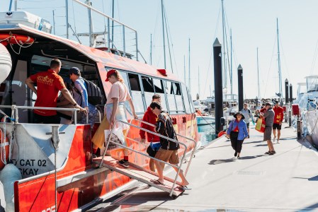 Guests in distance boarding Red Wildcat Vessel via accessible ramp at the Coral Sea Marina