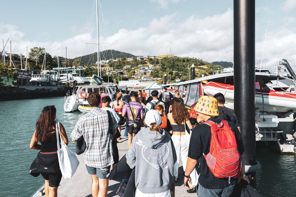 People walking on a pier about to embark on a red cat adventure tour in airlie beach wearing the correct clothing